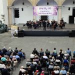 Orkiestra - artyści z instrumentami smyczkowymi oraz publiczność zgromadzona na dziedzińcu Zamku Piastów Śląskich