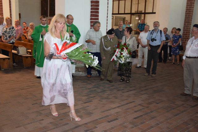Sekretarz Powiatu Brzeskiego Genowefa Prorok składa wieniec pod pamiątkową tablicą w kościele pw. św. Mikołaja